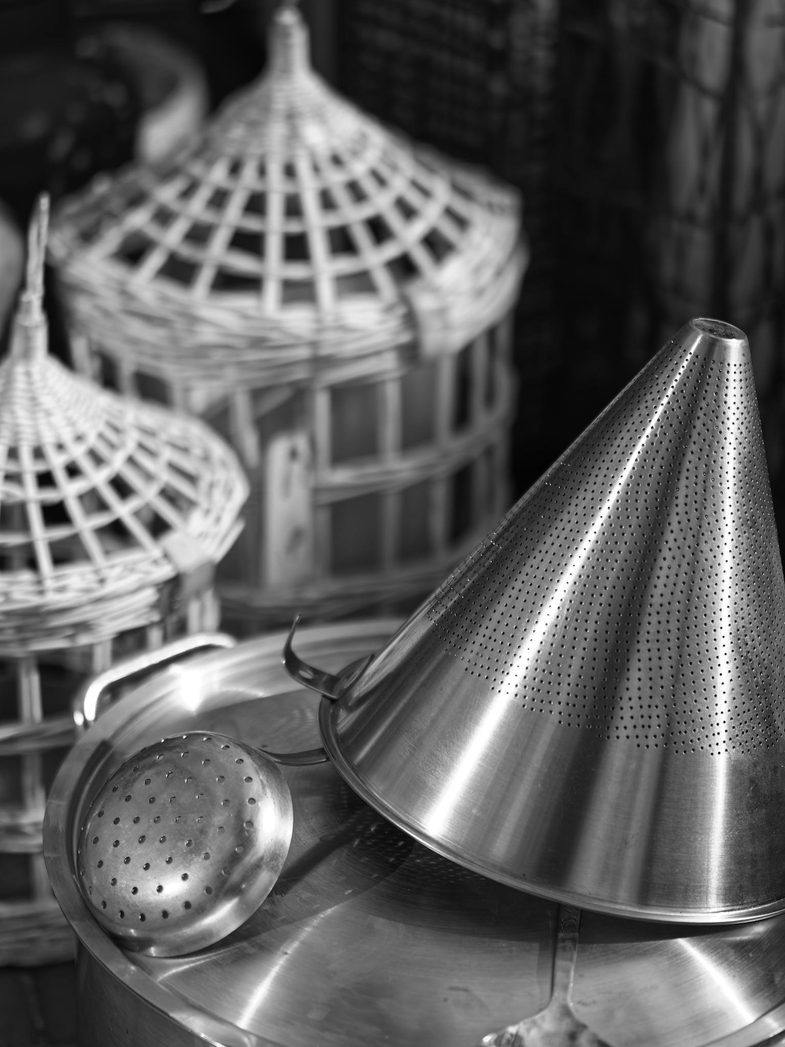 Close-up of conical and round stainless steel kitchen tools in monochrome.