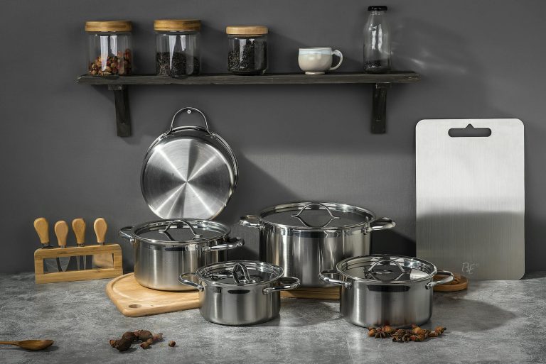 Stylish kitchen setup featuring stainless steel pots and kitchen accessories on a gray background.