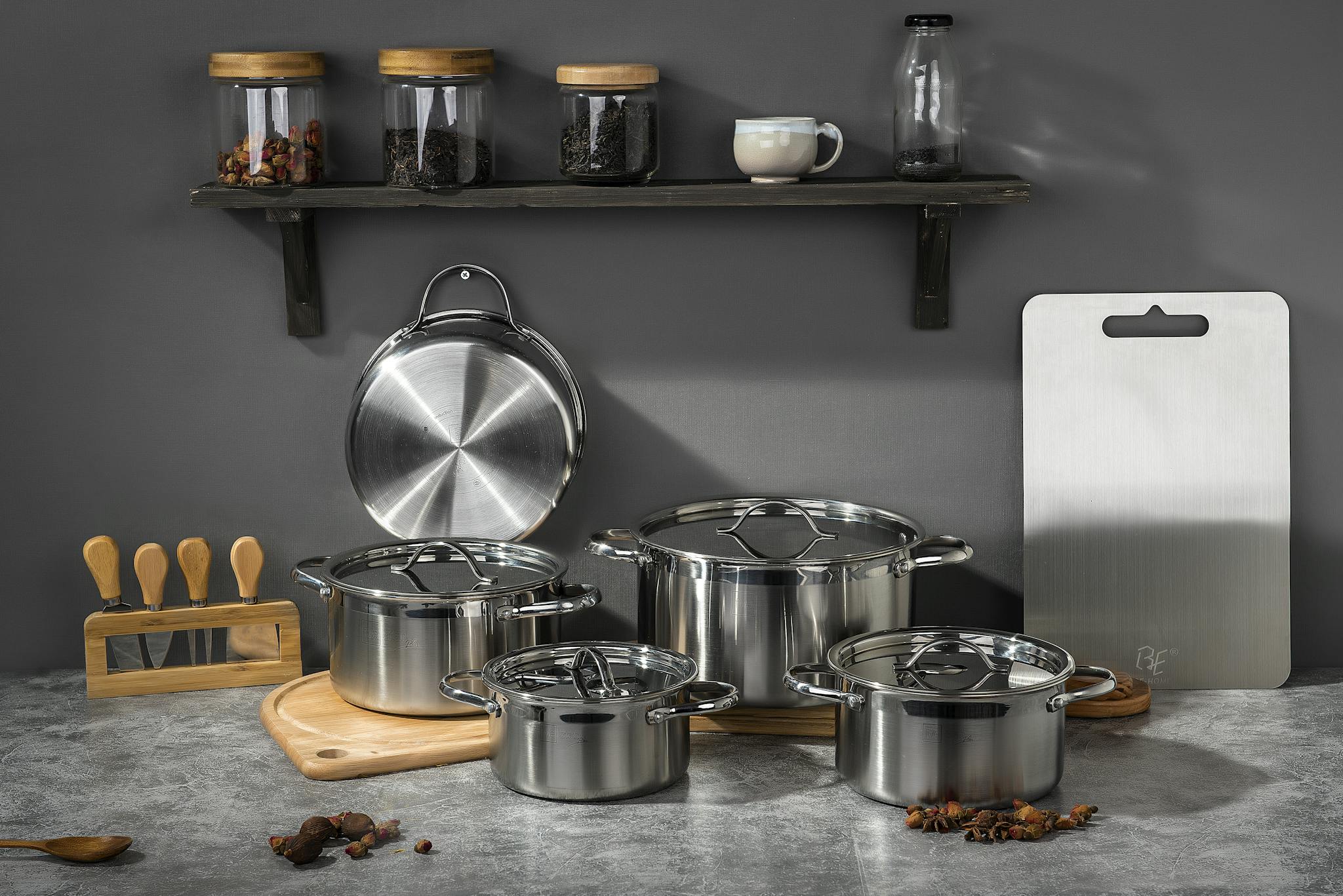 Stylish kitchen setup featuring stainless steel pots and kitchen accessories on a gray background.